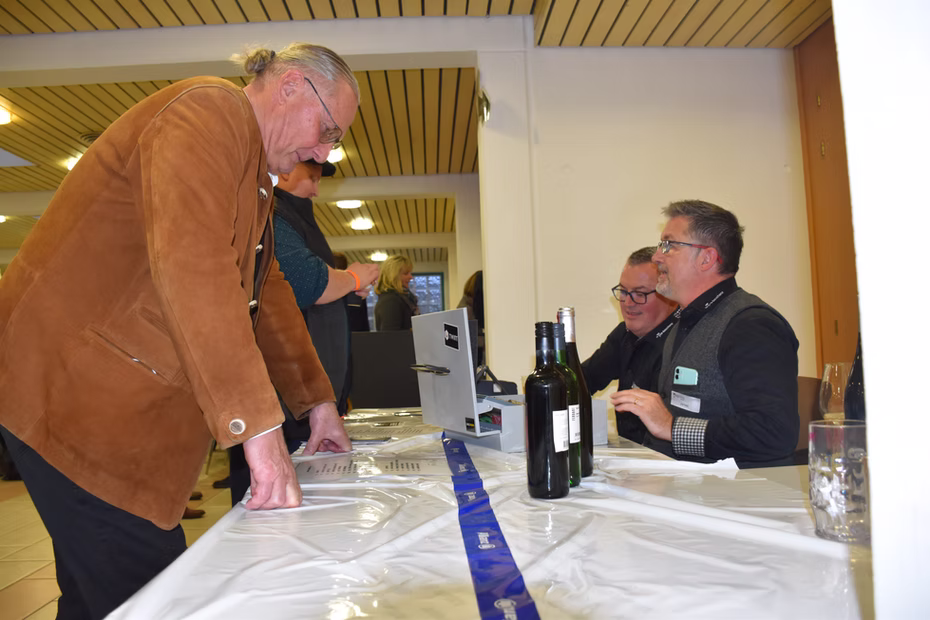 Un visiteur échange avec un exposant devant des bouteilles de vin.