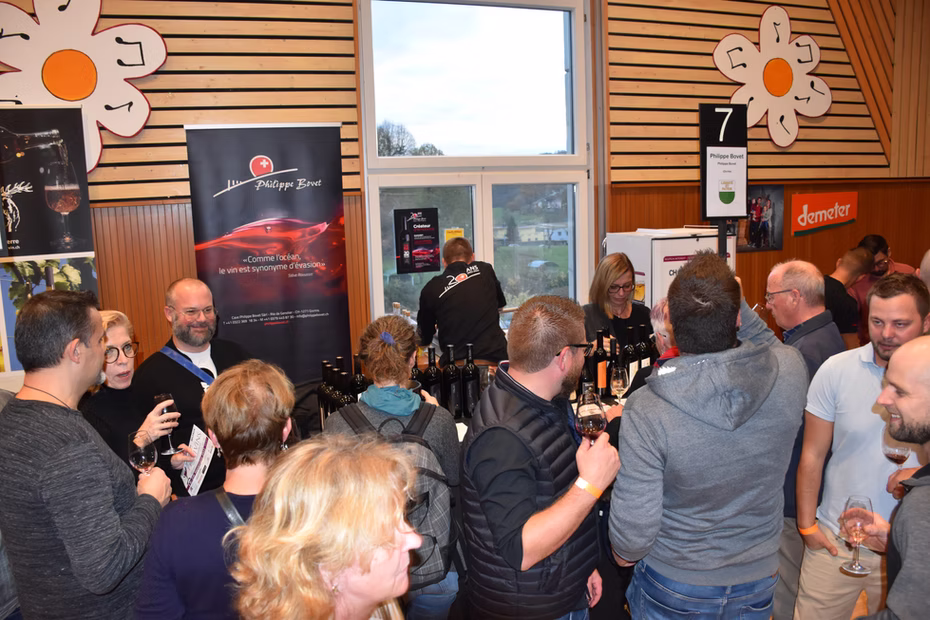 Des visiteurs dégustent du vin autour d'un stand de Festivins.